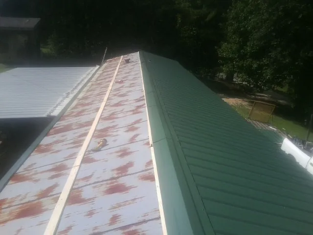 Old rusted panels beside newly installed green metal roofing — Wind Damage Roof Repair by Roofing Brothers in West Glacier