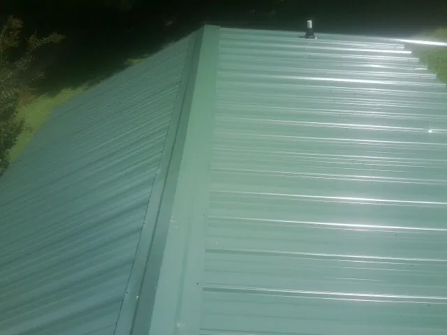 New green metal panels meeting at the ridge of a roof — Flat Roof Repair work by our crew in West Glacier