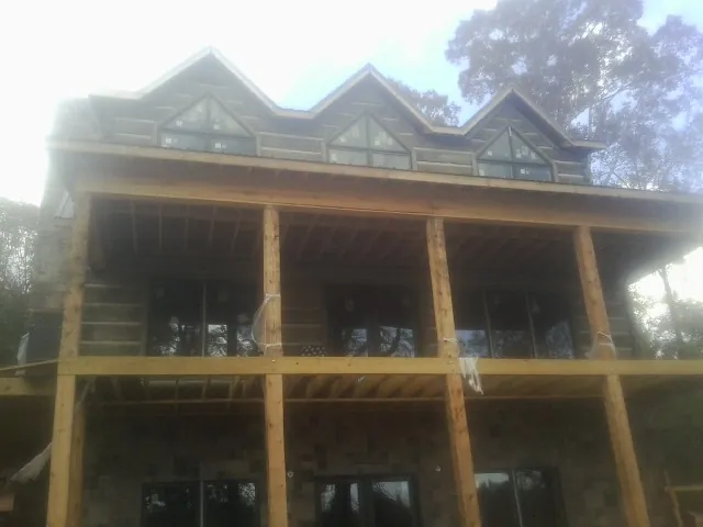 Dormers and porch framing on a large log home under construction — Roof Coating work by our crew in West Glacier