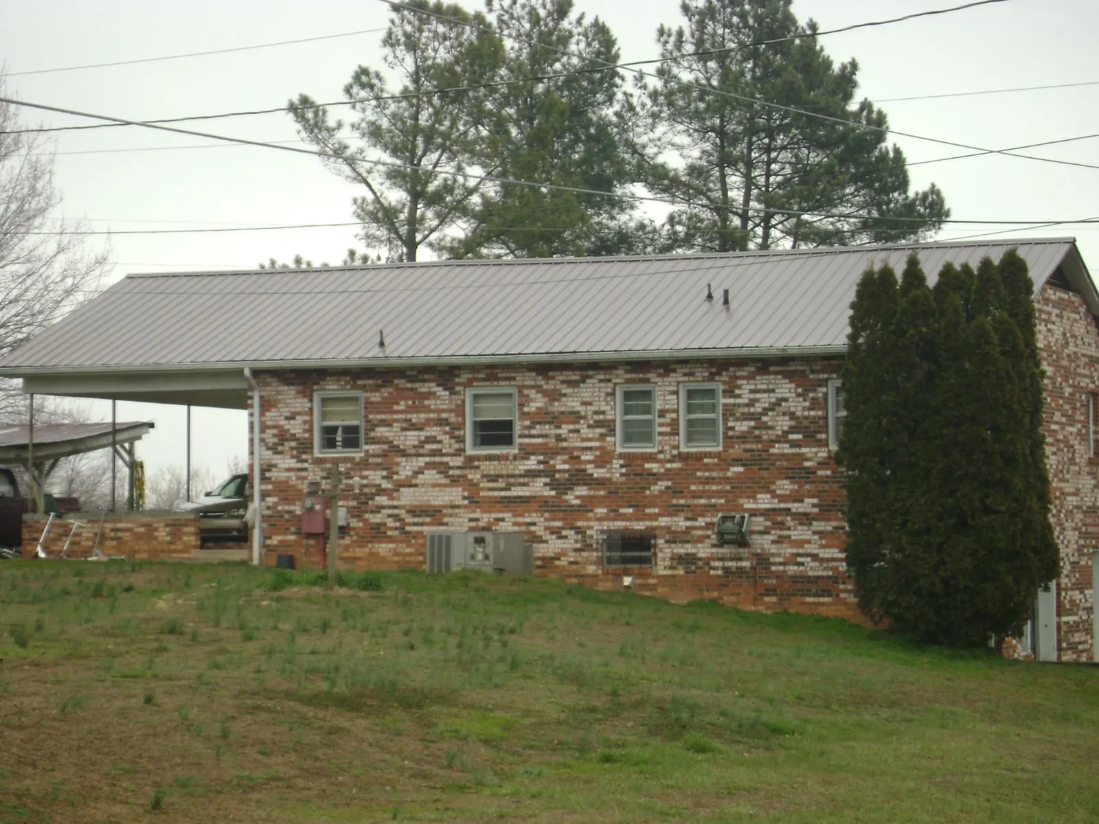 Gray metal roof on a brick split level home with a carport in West Glacier