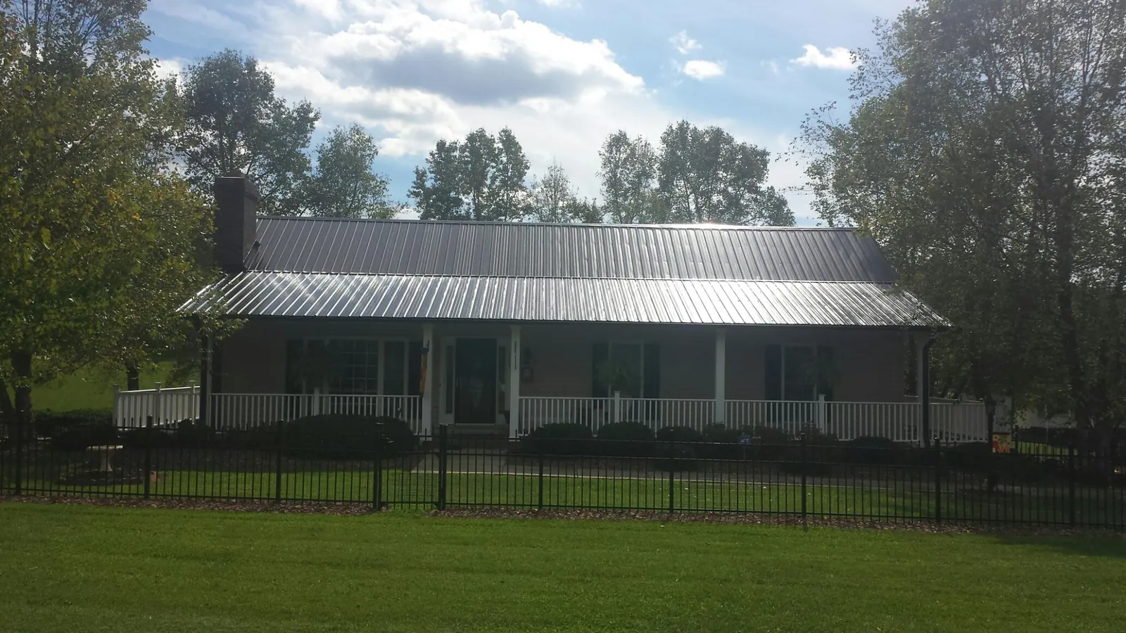 Gray metal roof on a brick ranch with a full width front porch — Gutter Guard Installation work by our crew in West Glacier