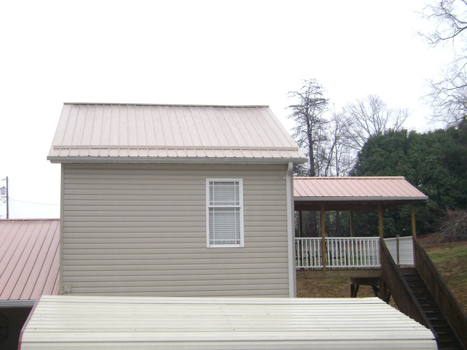 Tan metal roofs on a two story addition and attached porch, from a Roof Replacement job in West Glacier