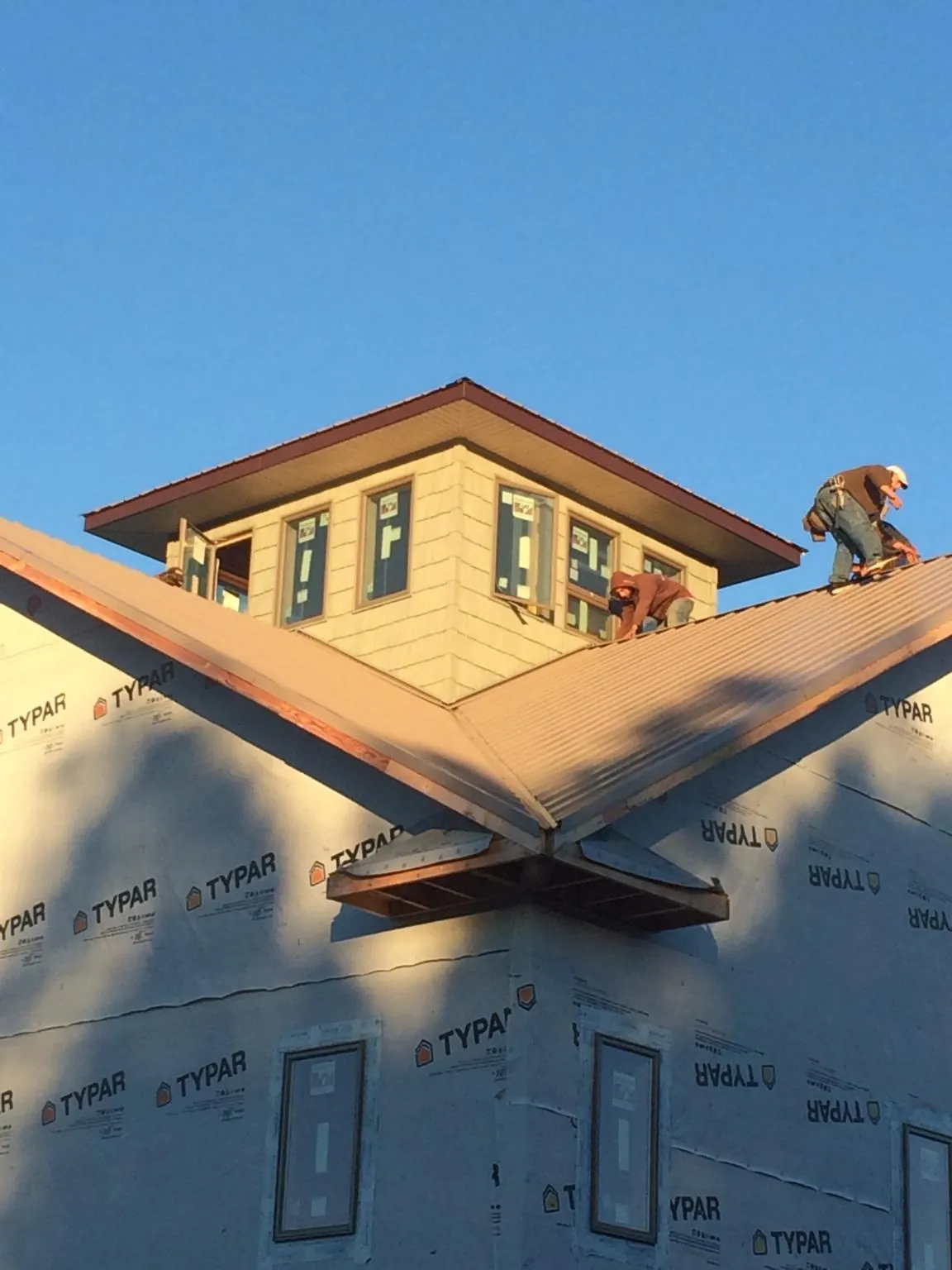Roofers working around a rooftop cupola on a new metal roof at sunset — Roof Waterproofing in West Glacier by Roofing Brothers